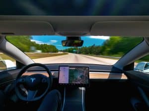 Someone driving a new Tesla Model 3 on autopilot