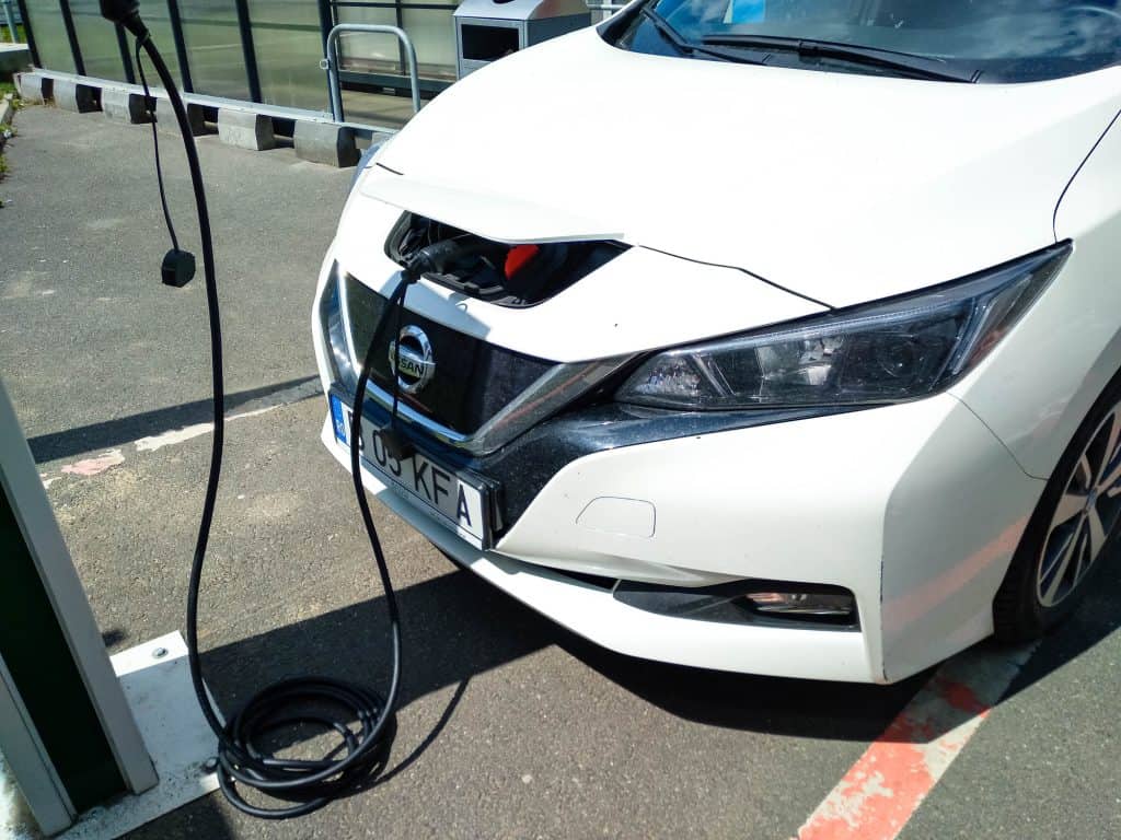 A charging cable going from an EVSE charging station into a Nissan Leafs charging port