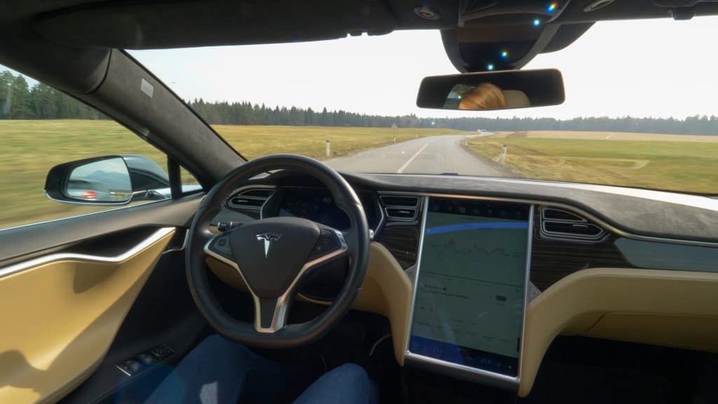 A tesla being driven in self driving mode no hands on the wheel