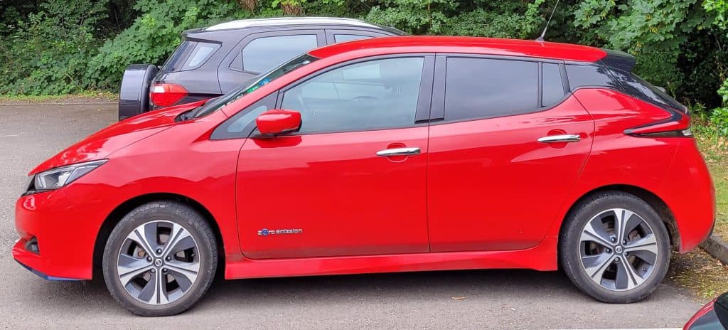 A side view of a red Nissan Leaf